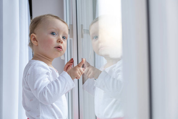 Kind blickt auf die Straße, die am Fenster steht. - Foto, Bild