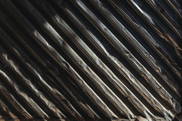 Texture of old crumpled metal corrugated sheets. The texture of aluminum corrugated board. Abstract background of metallic dark horizontal lines - Фото, изображение