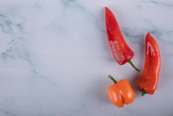 Three chili peppers on a blue marble table - Valokuva, kuva
