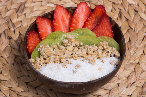 Leckere Smoothie-Acai-Schüssel aus Kokosnuss, Kiwi und Erdbeere mit geschnittenen Passionsfrüchten verziert. Serviert in einer Schüssel. Gesundes Leben Clean Eating Konzept - Foto, Bild
