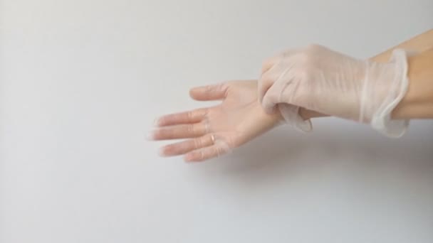 As mãos femininas tiram finas luvas de borracha transparentes após o uso como meio de proteger sua saúde contra vírus e bactérias. As luvas são descartadas após o uso. Mãos desprotegidas são perigosas
. - Filmagem, Vídeo