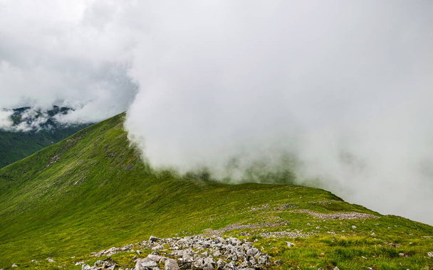 Δραματικό καλοκαίρι Scottish Highlands τοπίο. Χαμηλά σύννεφα κυλούν πάνω από την κορυφογραμμή του Beinn Eunaich, Dalmally, Σκωτία, Ηνωμένο Βασίλειο. - Φωτογραφία, εικόνα