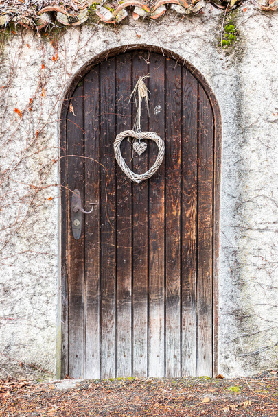 Старі дерев'яні двері в довгій кам'яній стіні
 - Фото, зображення