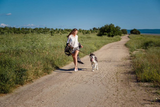 Urheilutyttö juoksee koiran kanssa siperianhusky tiellä. Onnellinen nainen käsite. Villi sielu. Siperian husky suosikki lemmikki
. - Valokuva, kuva