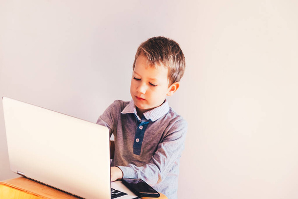Child working with his computer in his business, concentrated typing to succeed, funny image. - Photo, Image