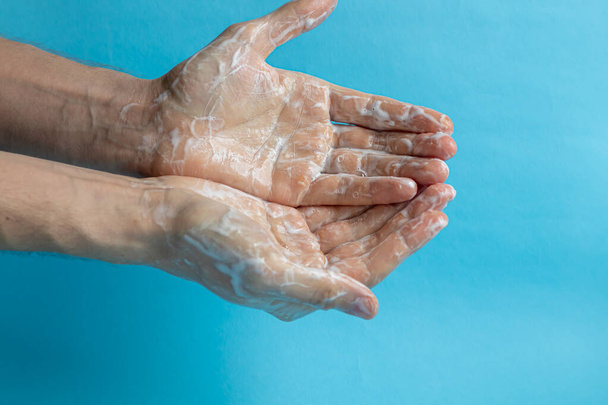 Ένας άντρας πλένει τα χέρια του με σαπούνι και χρησιμοποιεί αντισηπτικό για να καθαρίζει και να απολυμαίνει τα χέρια του. Πρόληψη ιών, κορονοϊός. Υγιεινή έννοια λεπτομέρεια χέρι. Καθαρότητα. - Φωτογραφία, εικόνα