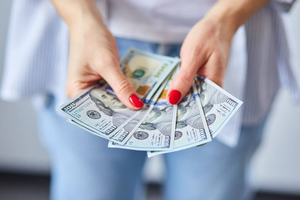 Μια γυναίκα κρατάει λεφτά στο χέρι. Έννοια της ευτυχίας, επιτυχία. - Φωτογραφία, εικόνα