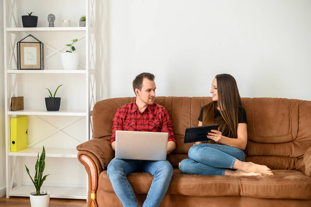 Young married couple on a sofa with gadgets - Foto, afbeelding