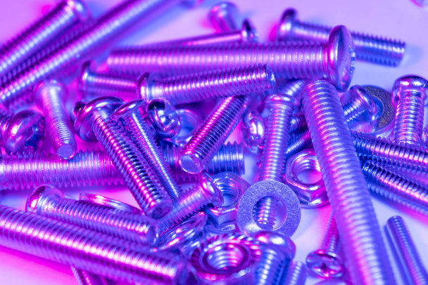 Metal bolts and nuts  in a row background. Chromed screw bolts and nuts in blue and pink tones. Steel bolts and nuts pattern. Set of Nuts and bolts. Tools for work. - Photo, Image