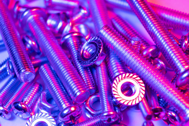 Metal bolts and nuts  in a row background. Chromed screw bolts and nuts in blue and pink tones. Steel bolts and nuts pattern. Set of Nuts and bolts. Tools for work. - Foto, imagen