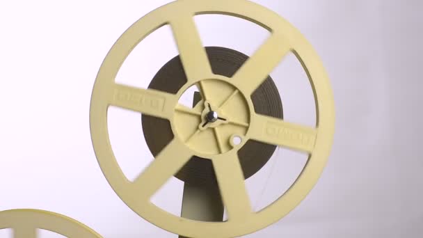 Una bobina di film gira su un proiettore cinematografico con uno sfondo bianco
. - Filmati, video