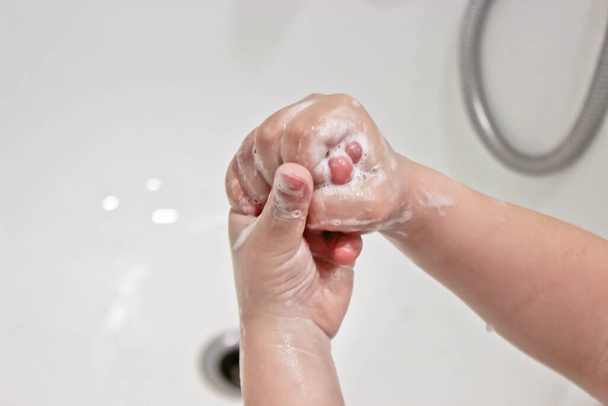 Children's soapy hands on a white bath - Foto, Imagem