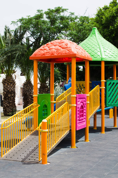 Çevresi yeşil ağaçlarla çevrili parktaki renkli çocuklar için çocuk parkı aktiviteleri. Çocuksuz oyun alanı - Fotoğraf, Görsel