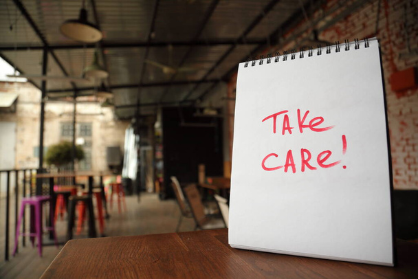 Take care text written on a paper on the street cafe table - Foto, Bild