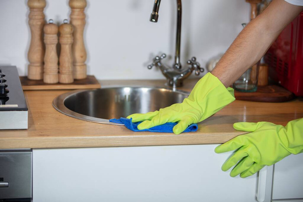 A closeup of a person disinfecting the kitchen sink with gloves - coronavirus concept - Foto, Bild