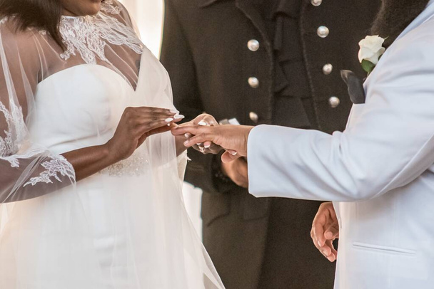 A closeup shot of the bride putting the wedding ring on groom's ring finger on a wedding - Photo, Image