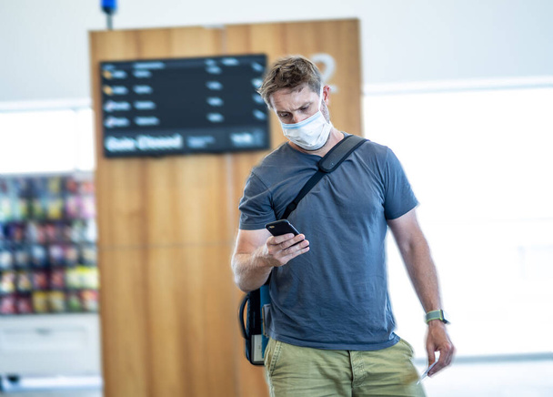 Coronavirus outbreak travel restrictions. Travelers with face mask at international airport affected by flights cancellations and travel ban. COVID-19 pandemic worldwide border closures and shutdowns. - Фото, изображение
