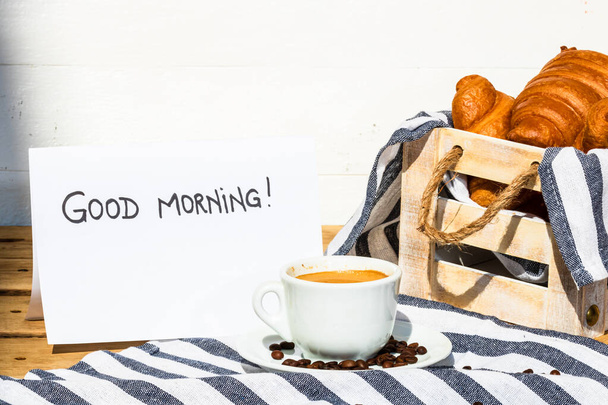 コーヒーカップと木のクレートに新鮮なフランスのクロワッサンをバター。食事と朝食のコンセプト。ホワイトボード上の朝のメッセージ - 写真・画像