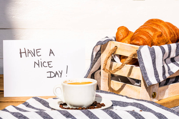 Filiżanka kawy i masło francuskie rogaliki na drewnianej skrzyni. Koncepcja jedzenia i śniadania. Poranna wiadomość na białej tablicy - Zdjęcie, obraz