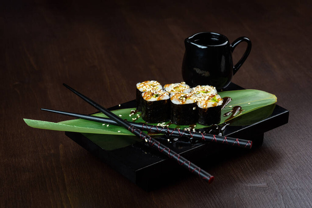 Rolls with eel on the board with sauce and chopsticks - Fotoğraf, Görsel