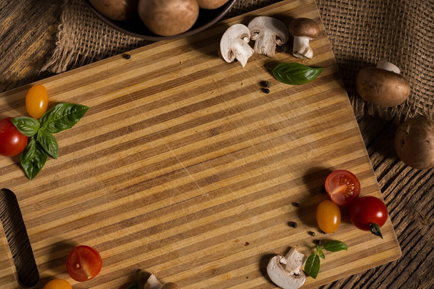 Ξύλινη πλάκα μπαμπού στο παλιό ρουστίκ ξύλινο τραπέζι με μανιτάρια, λαχανικά για γραφικά με χώρο αντιγραφής - Φωτογραφία, εικόνα