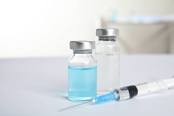 Vials and syringe on light background. Vaccination and immunization - 写真・画像