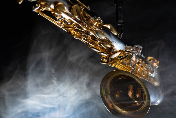 Golden shiny alto saxophone on black background with smoke. copy space - Photo, image