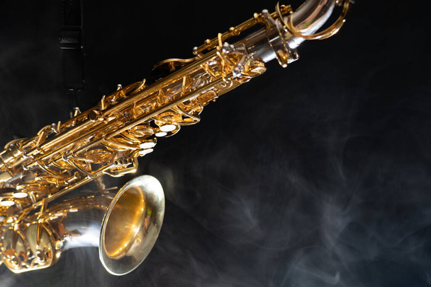 Golden shiny alto saxophone on black background with smoke. copy space - Foto, afbeelding
