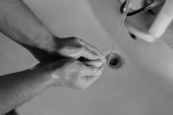 mensen wassen handen in wastafel met een stuk zeep om coronavirus ziekte te doden met alcohol-gebaseerde hand ontsmettingsmiddel en antibacteriële zeep om ziektekiemen te bestrijden in een stromend water. Blijf thuis en was je handen. - Foto, afbeelding