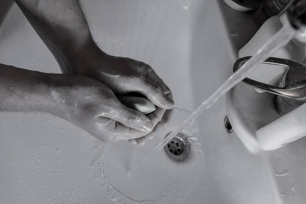 Ihmiset pesevät kätensä pesualtaassa saippualla tappaakseen sepelvaltimotaudin alkoholiin perustuvalla käsienpuhdistusaineella ja antibakteerisella saippualla torjuakseen bakteereja juoksevassa vedessä. Pysy kotona ja pese kätesi.
 - Valokuva, kuva
