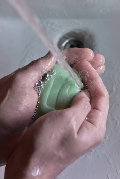 people washing hands in sink with a bar of soap to kill coronavirus disease with Alcohol-based hand sanitizer and antibacterial soap to fight germs in a running water. stay home and wash your hands - Photo, Image