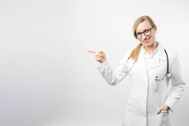Woman in medical uniform pointing with finger to empty space - 写真・画像