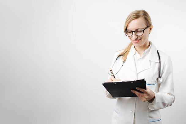 Médica sorridente em óculos escrevendo na área de transferência
 - Foto, Imagem