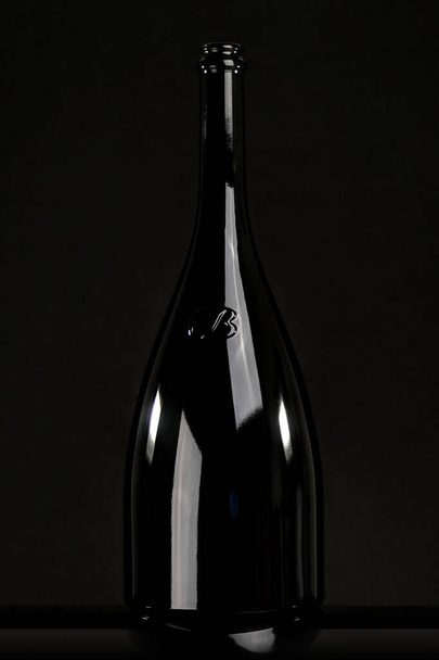 Bouteille de vin en verre noir sur fond noir, nature morte
 - Photo, image