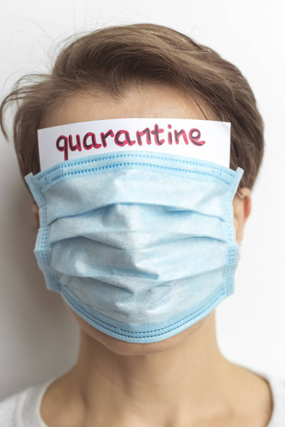 Woman is protected by a medical mask respirator with the inscription Quarantine. - 写真・画像