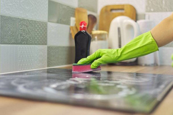 Primo piano della mano donna pulizia moderna cottura in vetro ceramica superficie elettrica con spugna e detergente
 - Foto, immagini