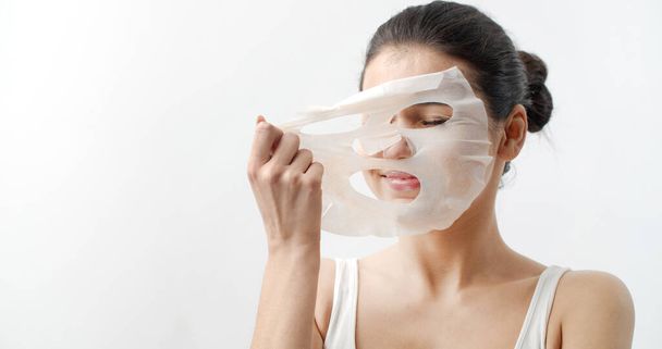 Female removing face sheet mask - Foto, afbeelding