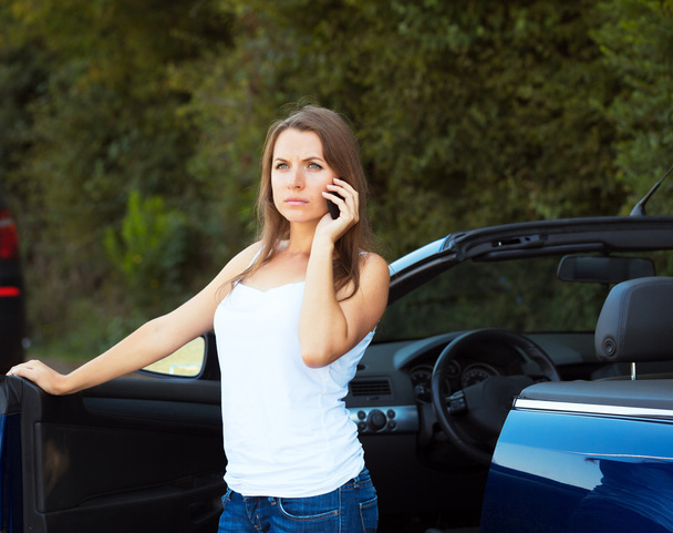 Caucasian girl on a cell phone service or tow truck traffic near - Foto, Imagen