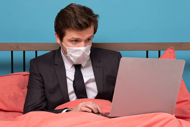 Un homme couché au lit avec son ordinateur portable essayant de travailler sur la quarantaine. Plan studio
 - Photo, image