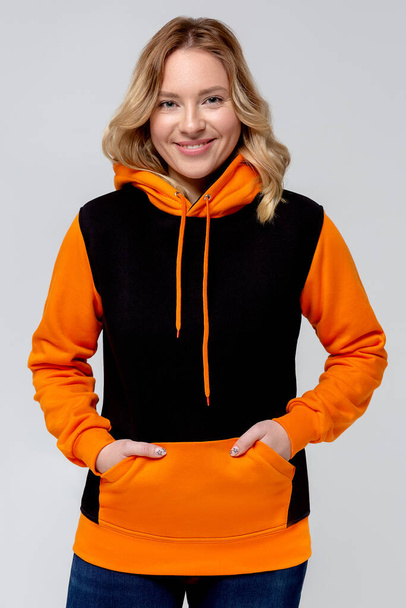 Frau in schwarzem und orangefarbenem Kapuzenpullover, Mockup für Logo oder Branding Design - Foto, Bild