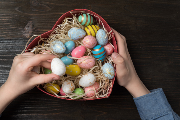 Childrens hands holding Heart shaped box with colorful Easter eggs. Easter gift concept. - 写真・画像