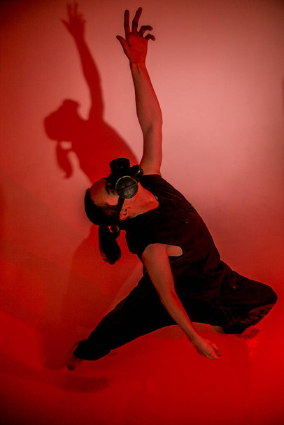 Чоловік у газовій масці на червоному тлі танцює
 - Фото, зображення