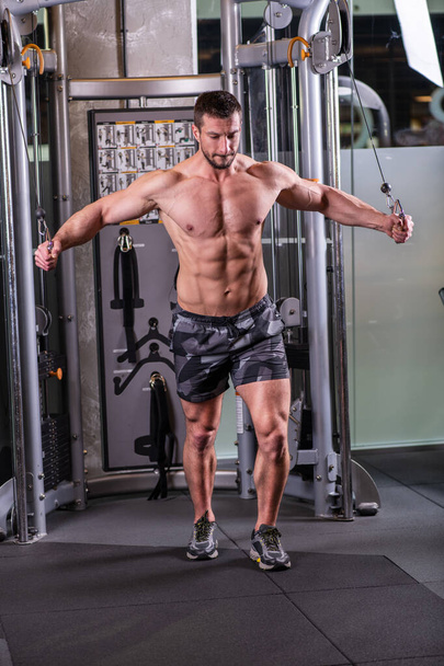 Sexy muscular man doing butterfly exercise for chest on the cable machine - Foto, imagen