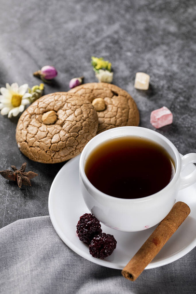 Egy csésze teát, mandulás sütit, bogyót, fahéjat és diót. - Fotó, kép