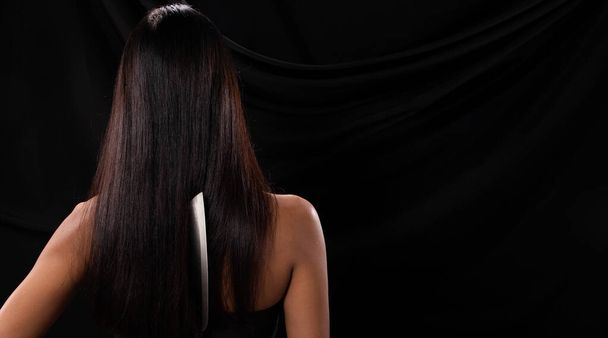 アジアの女性の背中側のビュー長い髪を保持キッチン鋭いナイフ手で、スタジオの照明黒の背景、ストライキによって裏切る準備ができて - 写真・画像