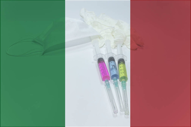 Tres jeringas médicas con líquidos azules, verdes y rojos. Bandera de Italia en segundo plano
. - Foto, imagen