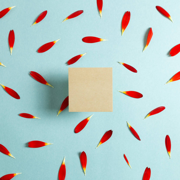 Almohadilla Kraft, papel vacío con pétalos de flores rojas sobre fondo azul. Composición floral, plano, vista superior, espacio para copiar
 - Foto, imagen