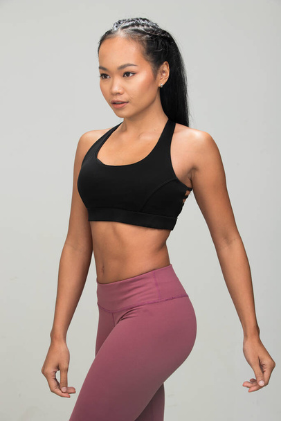 Asya Tan Cilt Fitness kadın egzersiz ısınmak kollar siyah spor sütyen dut mor pantolon giymek, stüdyo aydınlatma gri arka plan kopya alanı, konsept Woman Can Do Sport 6 paketleri - Fotoğraf, Görsel