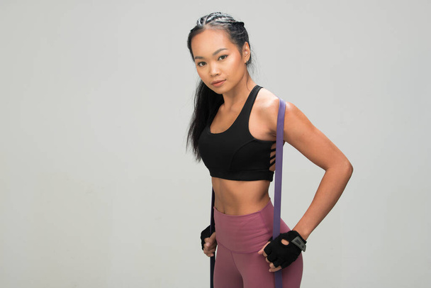 Asian Tan Skin Fitness Жінка займається розігріванням смуг опору на розтягненнях у чорних спортивних бюстгальтерах, студійним освітленням сірого фонового простору, концептом Woman Can Do Sport 6 пачок. - Фото, зображення