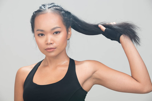Asian Tan Skin Fitness kobieta ćwiczenia trzymać dotyk włosy nosić rękawice bokserskie czarny sport biustonosz morwy fioletowe spodnie, studio oświetlenie szary tło przestrzeń kopia, koncepcja Kobieta może zrobić Sport 6 opakowań - Zdjęcie, obraz